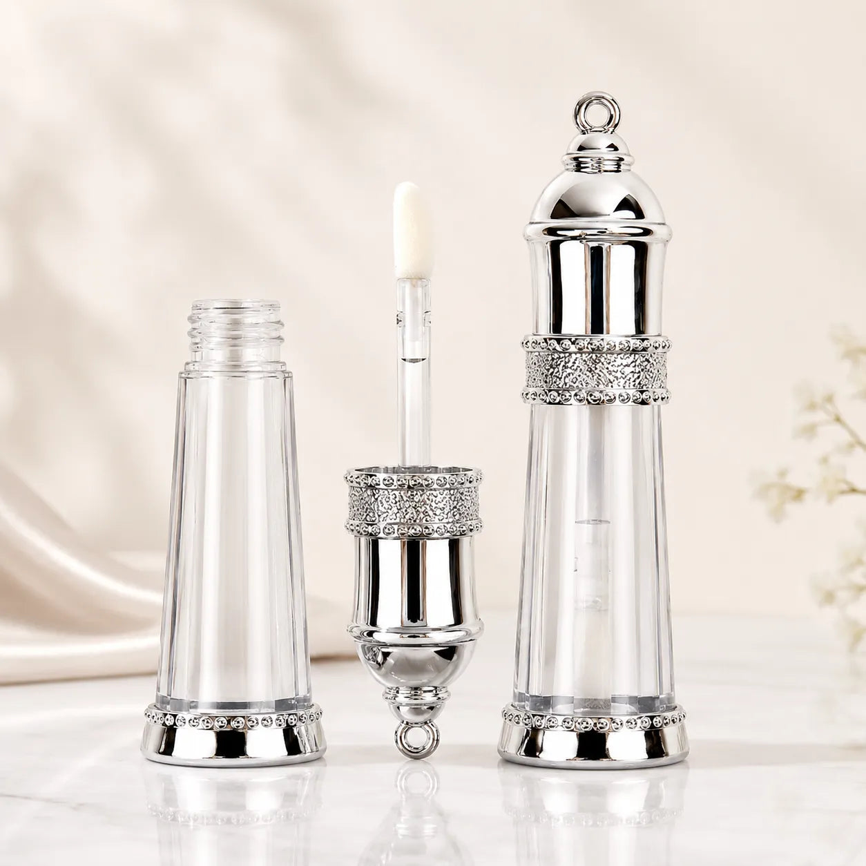 Clear lip gloss containers with luxury silver details and transparent bottle packaging.