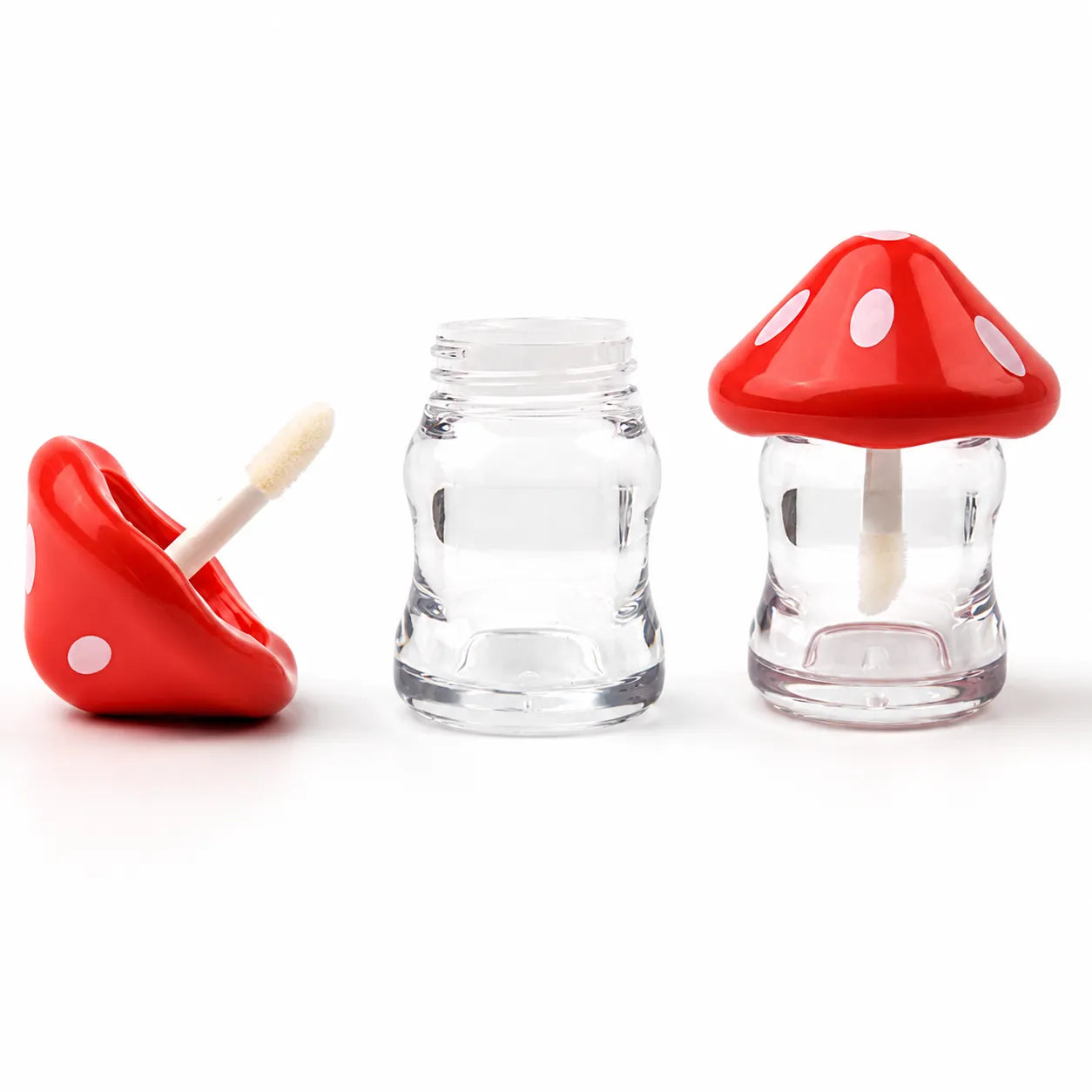 Kaiya cute lip gloss containers with red mushroom-shaped caps, clear lower jars, and matching applicator pieces.
