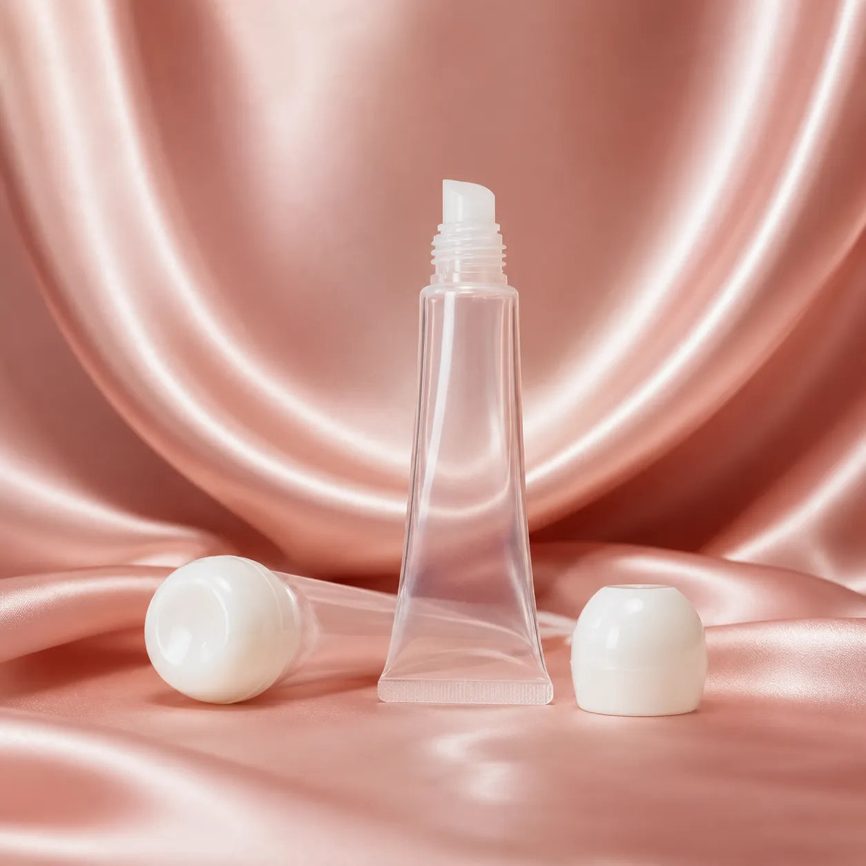 Clear lip gloss squeeze tubes with empty transparent packaging and white caps by Kaiya