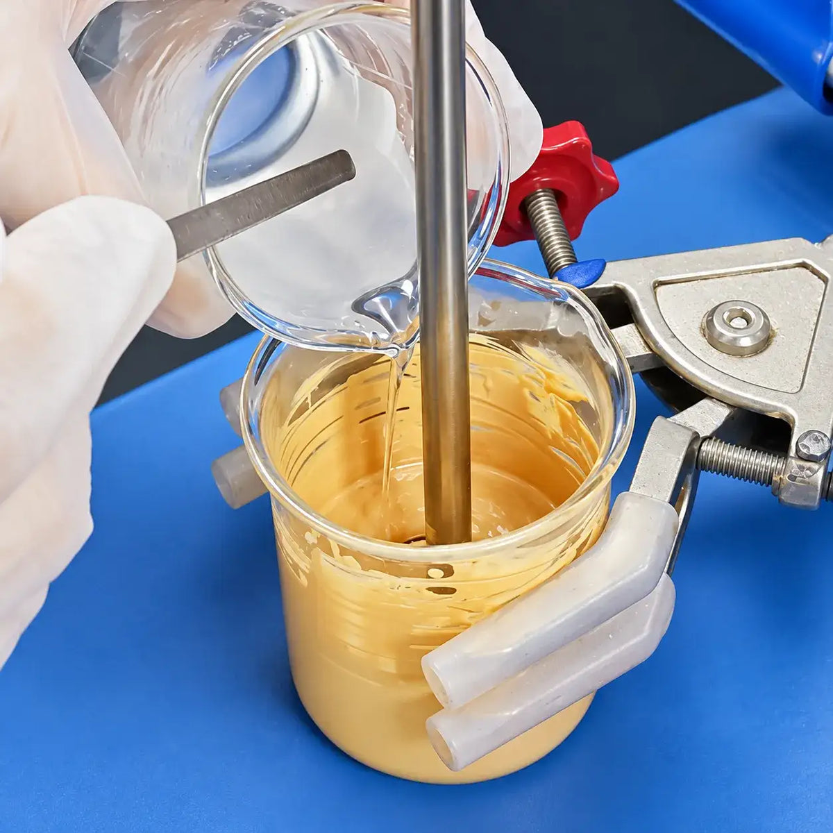 KAIYA concealer formula development with ingredients added to a mixing beaker during laboratory sampling.