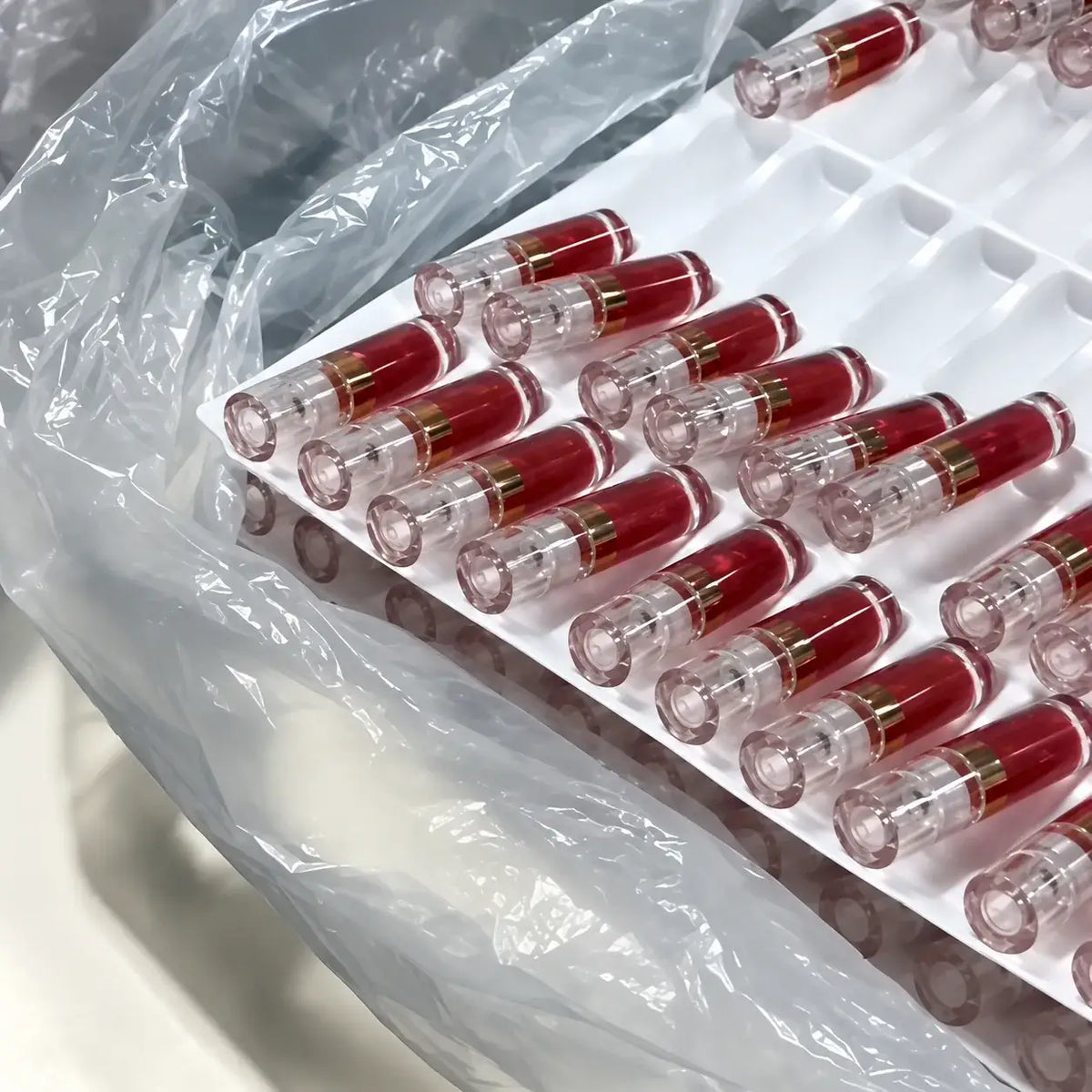 Rows of clear tubes filled with red lip tint arranged in production trays at KAIYA.