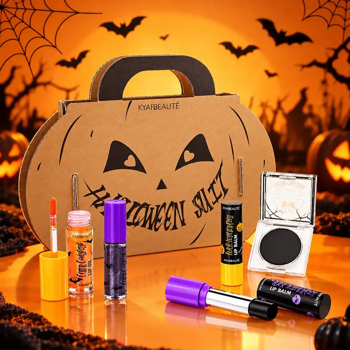 Halloween lip balms, lip oil, lip gloss and a blush compact displayed beside a pumpkin-shaped carry box.