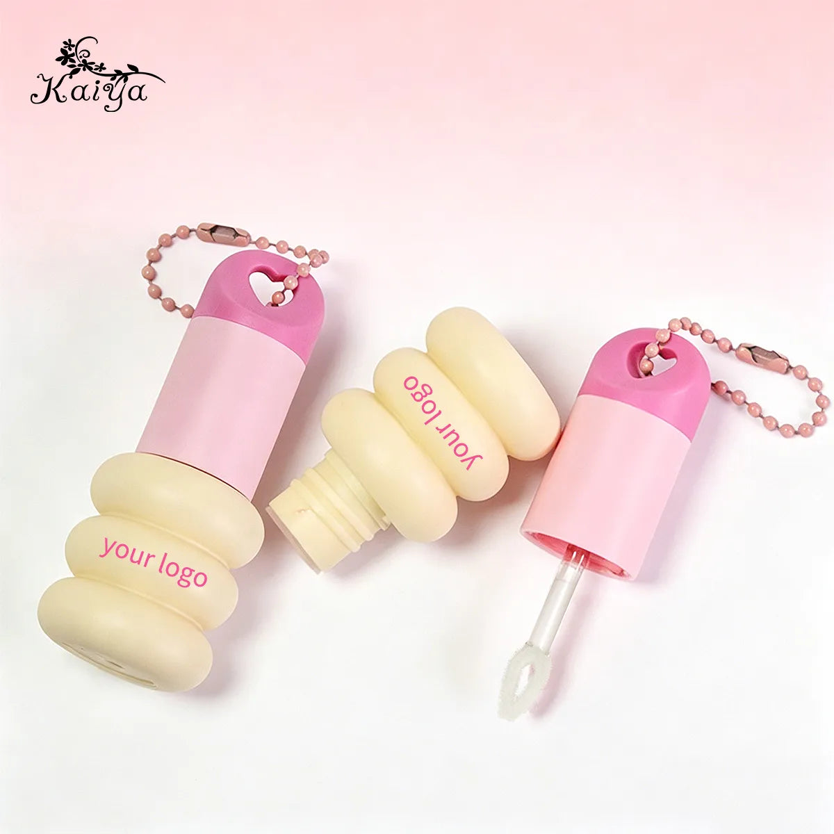 Keychain lip gloss tubes with spray-coated pink surfaces, detachable caps, decorative bead chains and applicator components by KAIYA.