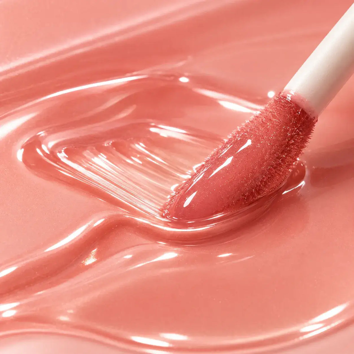 Kaiya lip gloss formula and flocked applicator shown in a peach gloss texture