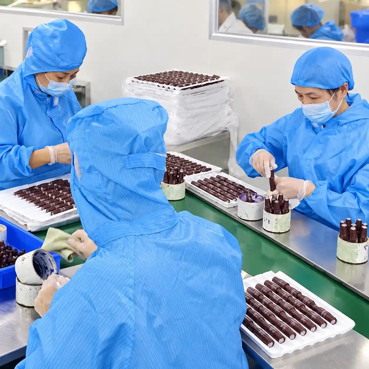 KAIYA workers organizing filled lip oil tubes on a cosmetics production line.