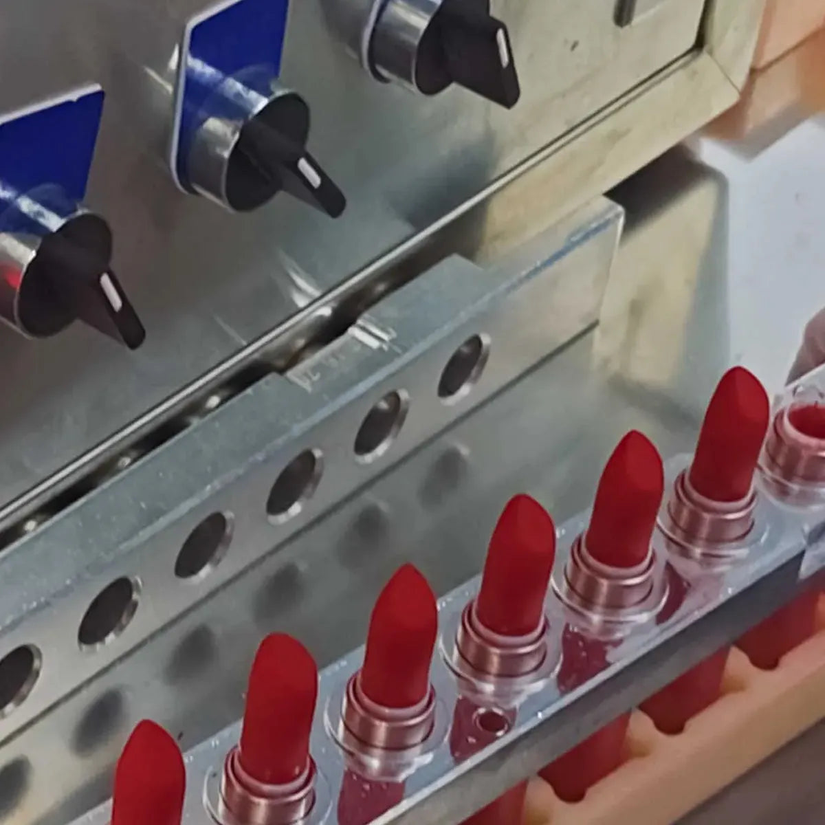 KAIYA lipstick manufacturer assembling red lipstick bullets on a bulk production line.