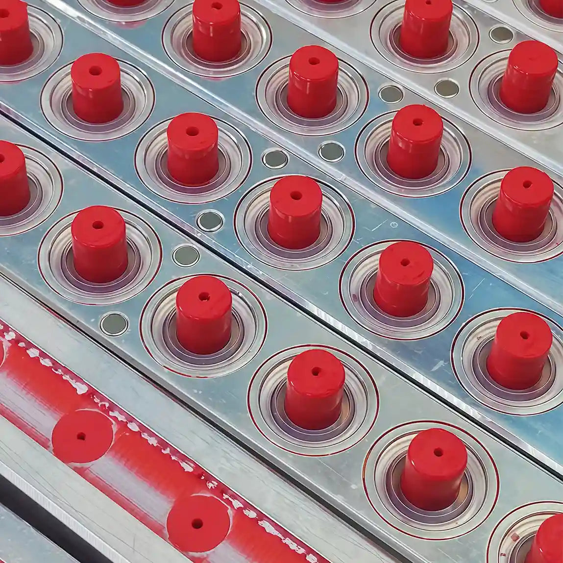 Red lipstick bullets arranged in metal production molds at KAIYA, a lipstick manufacturing company.