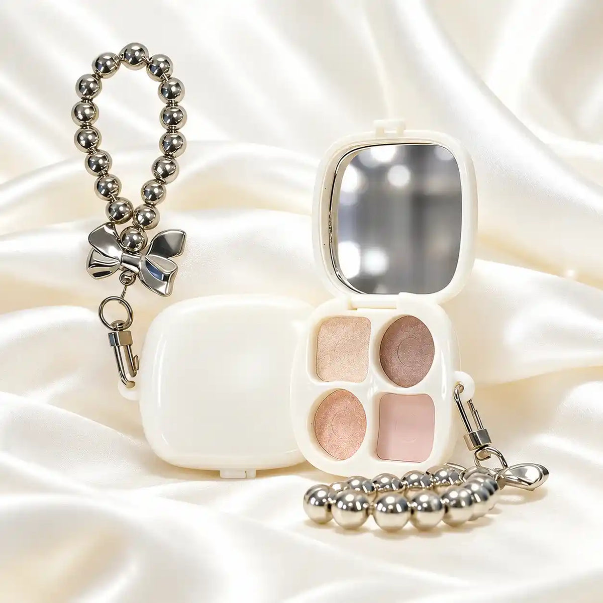 KAIYA four-pan private label eyeshadow palette with matte and shimmer shades, a mirror and a silver-colored bead charm.