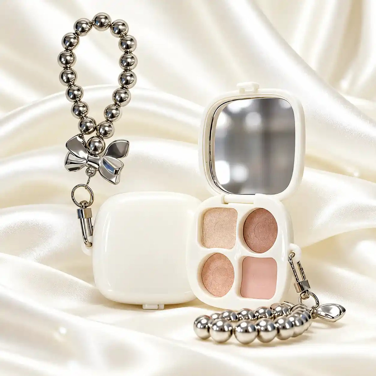 Four-pan wholesale highlighter palette in a white mirrored compact with champagne, bronze and pink shades and a bead-chain accessory.
