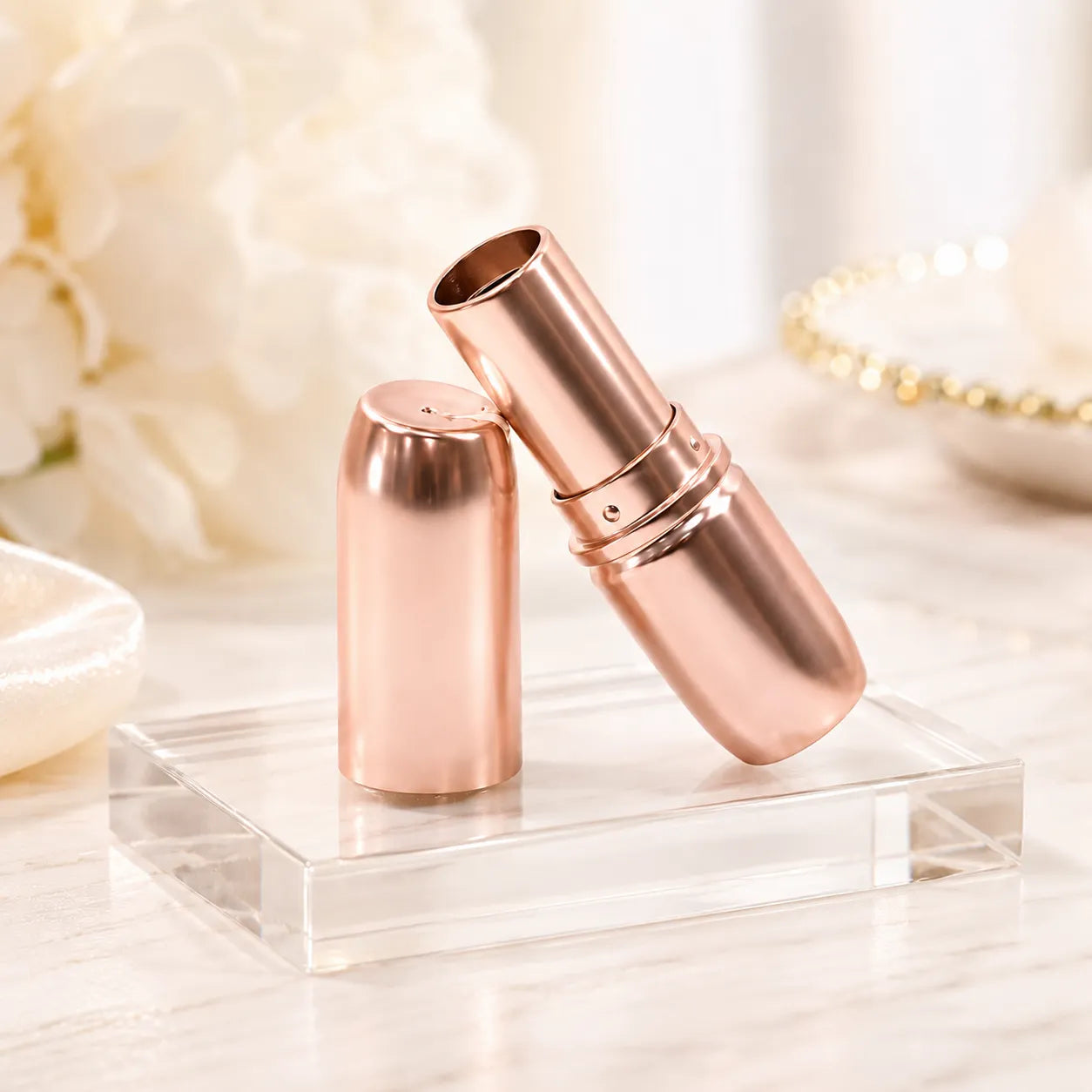 Rose gold lipstick packaging with metallic lipstick tube, empty inner cup, matching cap, and transparent display stand for luxury cosmetic brands