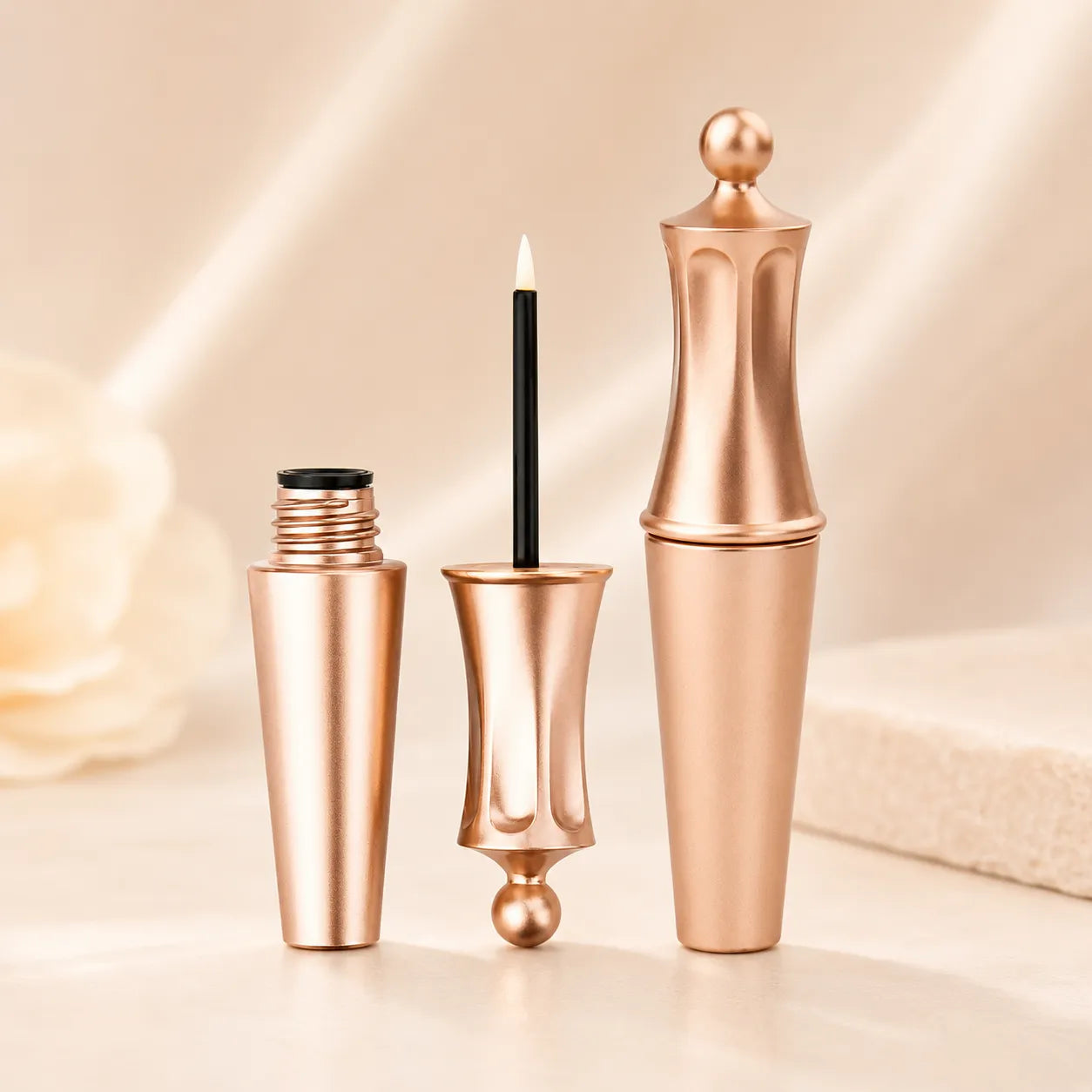 Empty eyeliner tubes in rose gold color with matching caps, slim clear bodies, and premium packaging for custom eye makeup brands