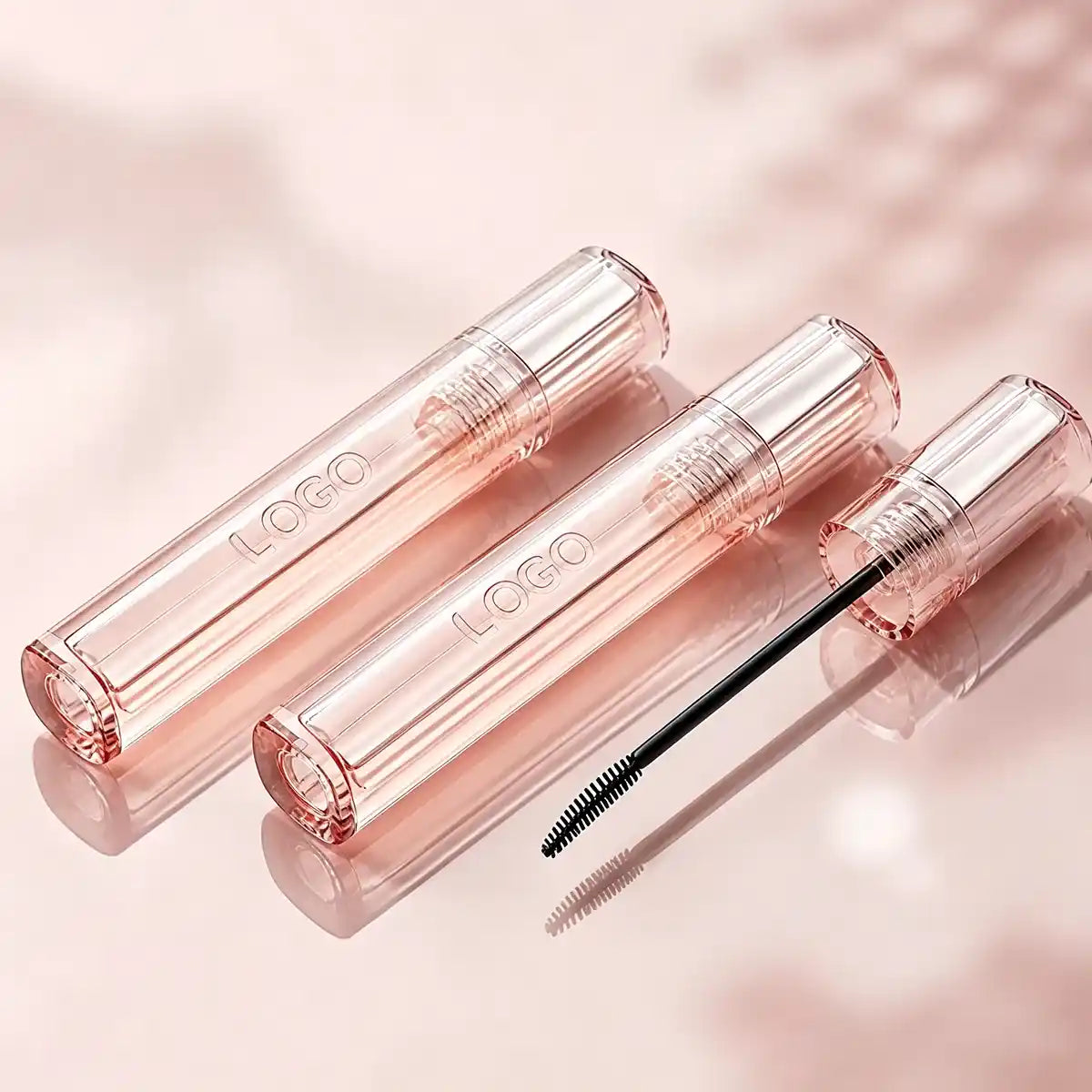 Empty mascara tube with laser engraving logo detail, clear pink tube body, and slim mascara brush for custom eye makeup packaging.