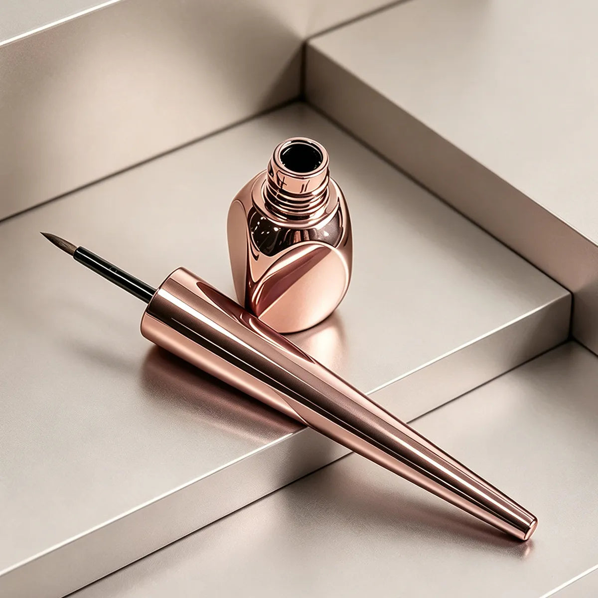 Eyeliner bottle in rose gold color with clear tube body, slim applicator, and luxury cosmetic packaging design