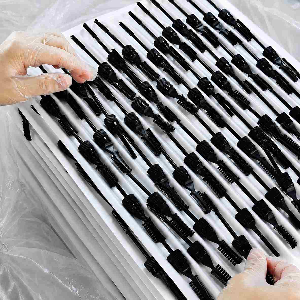 Custom makeup packaging by KAIYA, showing black mascara brush components arranged in trays for cosmetic packaging production.