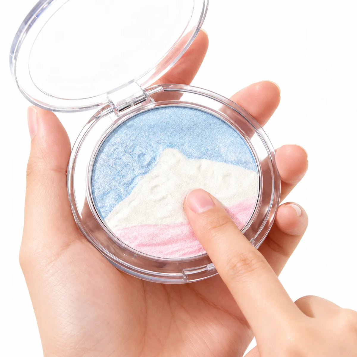 Finger touching a three-color putty highlighter with a raised mountain design in blue, white and pink inside a clear compact.