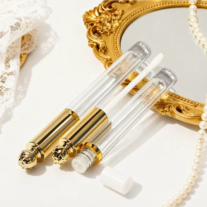 Diamond lip gloss tubes with gold lip gloss containers, featuring a decorative crystal-style cap and clear bottle design for custom lip gloss packaging.