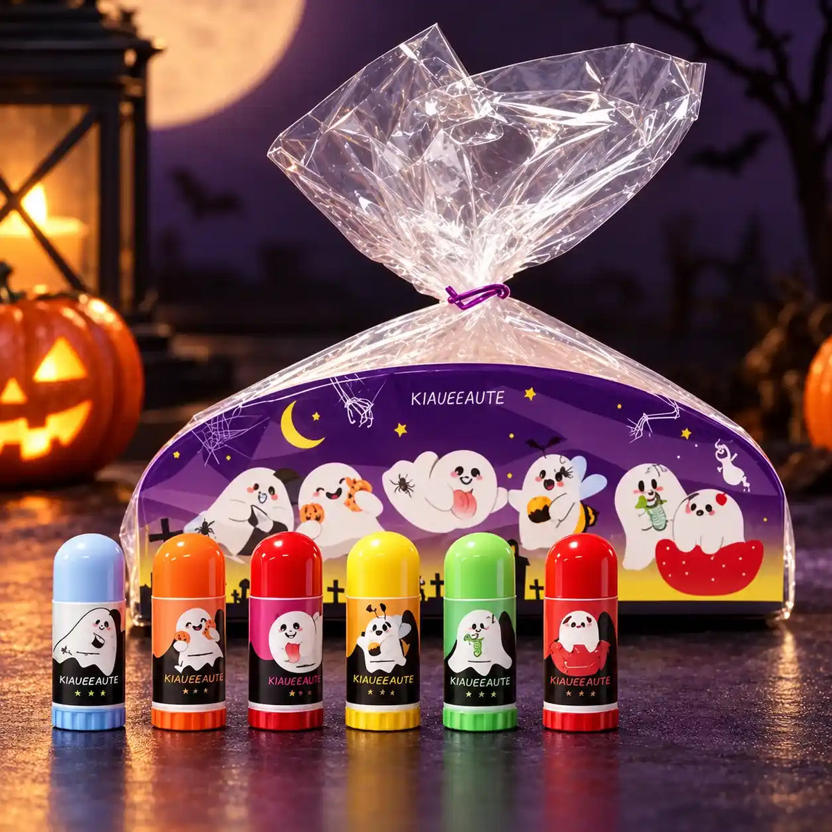 Colorful mini lip balms with ghost labels beside a purple Halloween gift bundle wrapped in clear film.