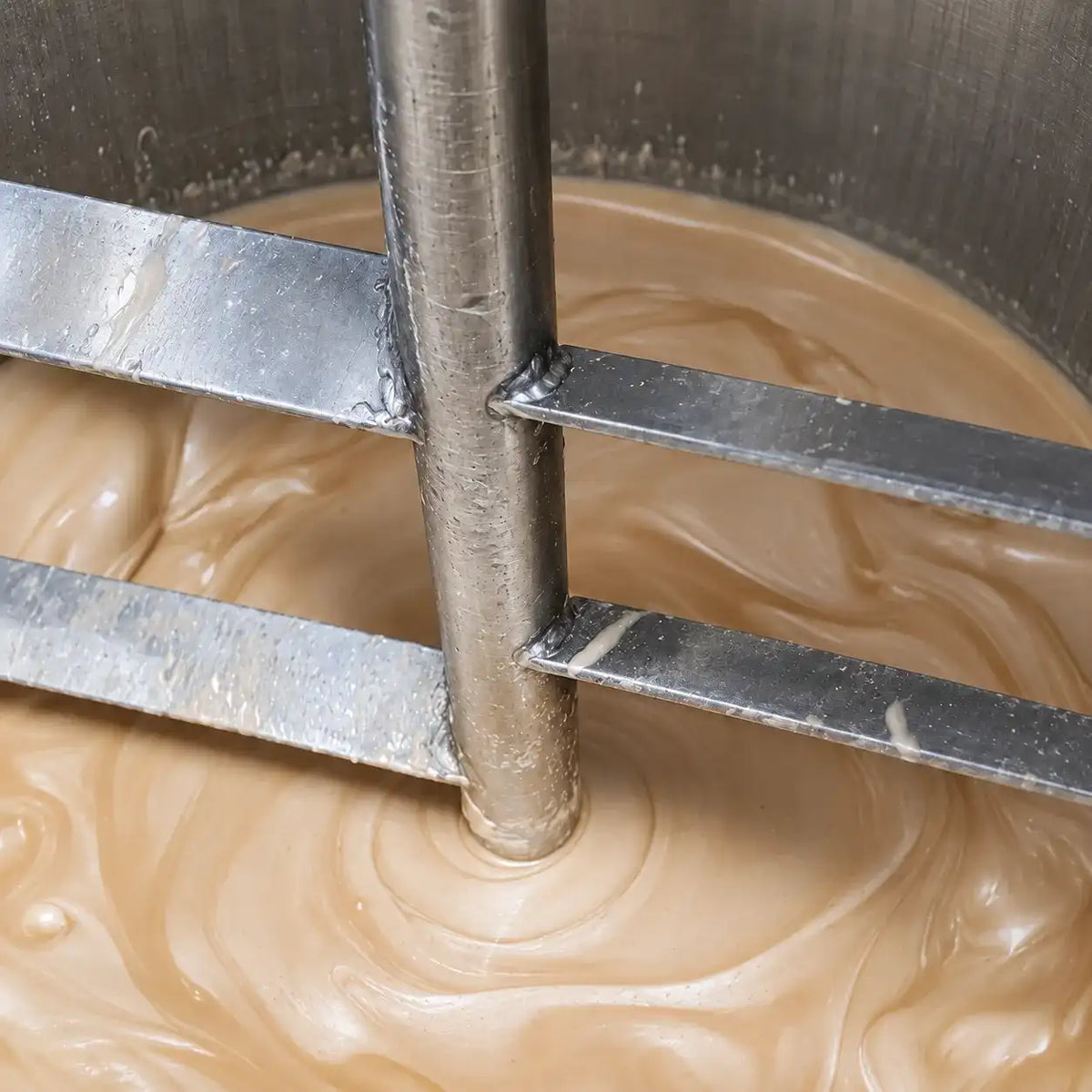 Champagne-colored highlighter formula being mixed in a stainless steel production vessel at KAIYA.