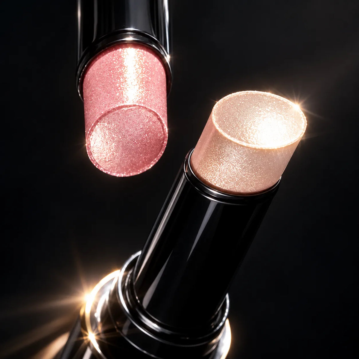 Pink and champagne jelly highlighter sticks in black tubes, shown close up with sparkling surfaces.