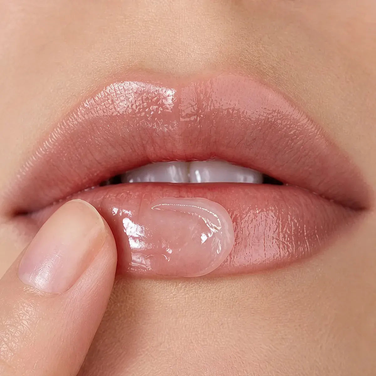 Close-up of lip balm spreading smoothly across the lips with moisture, shine and a cushioned after-feel.