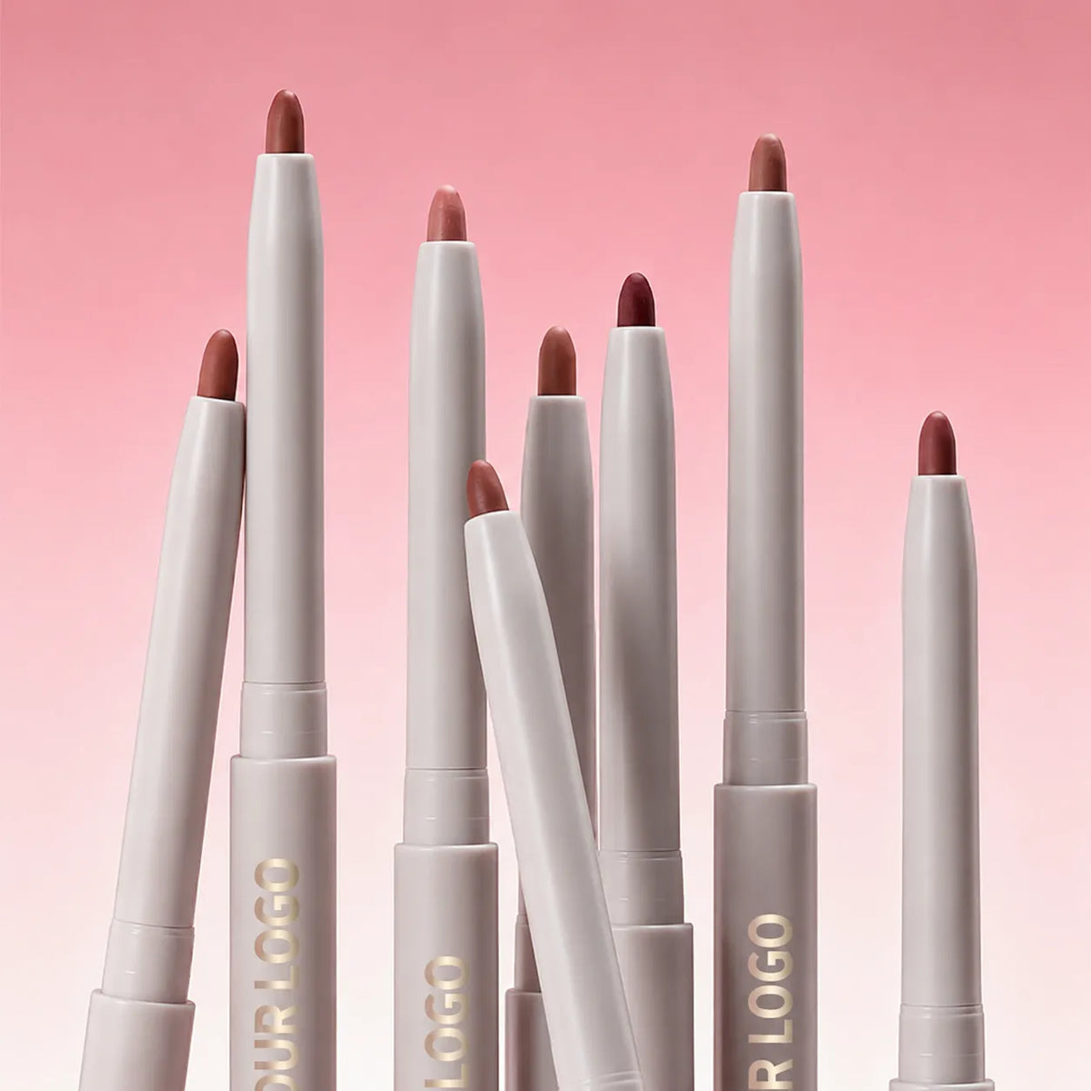 White lip liner pencils with exposed nude, pink and brown tips standing against a pink background.