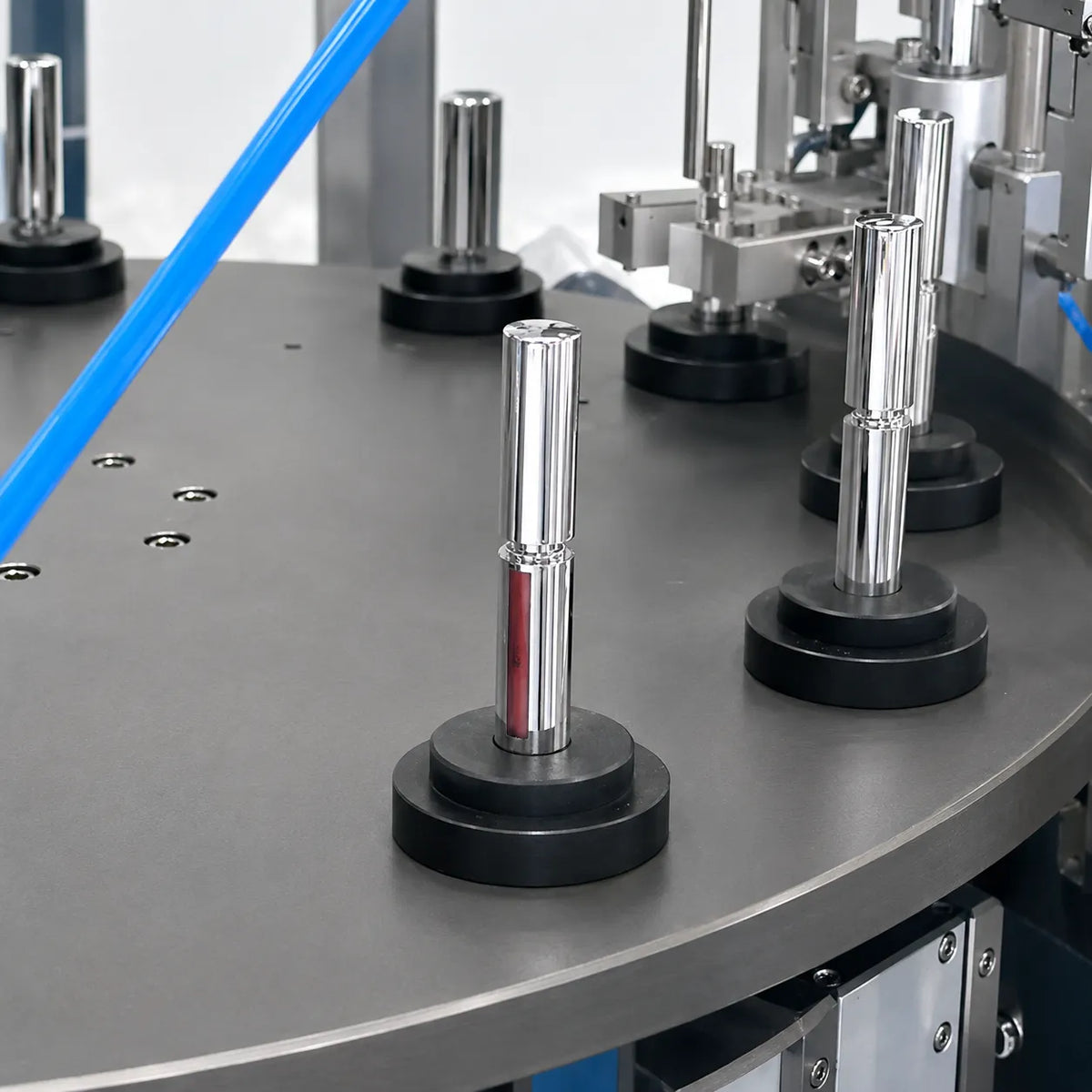 Liquid lipstick tubes positioned on rotary manufacturing equipment for automated component handling