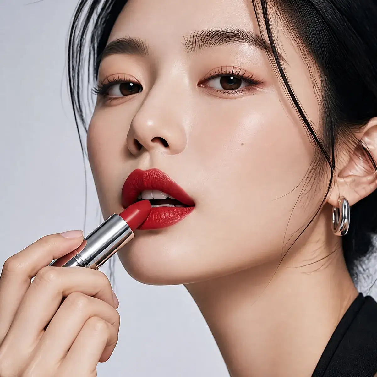 Model applying red lipstick to show smooth glide, even coverage and rich color payoff.