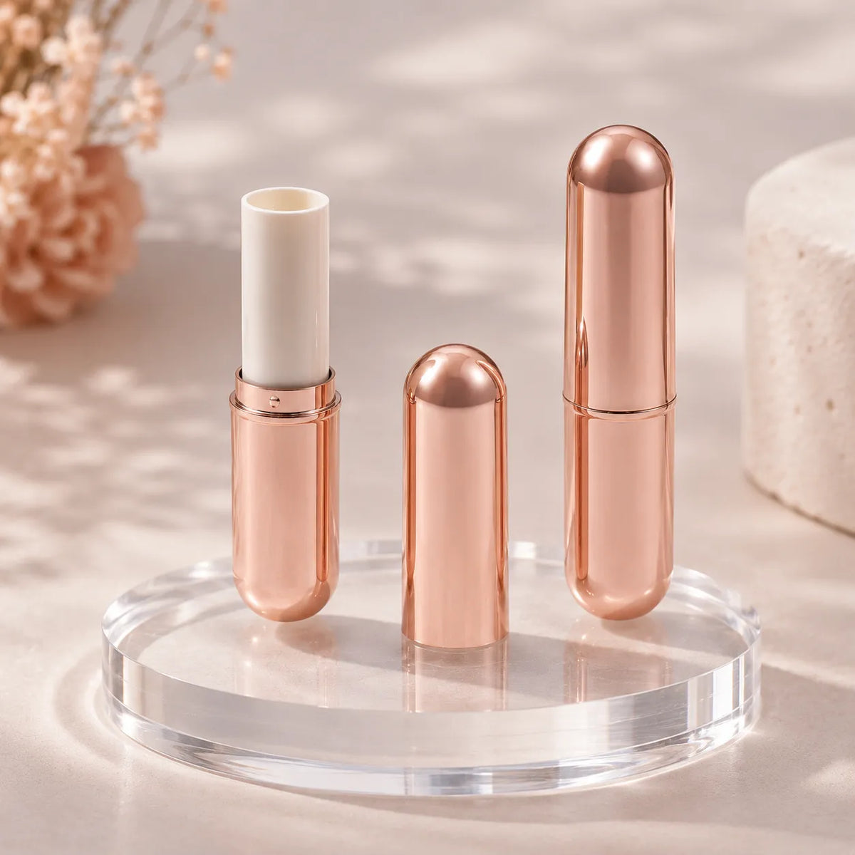Rose gold lipstick tubes displayed in a clean luxury product scene, showing elegant empty lipstick packaging in open and closed styles.