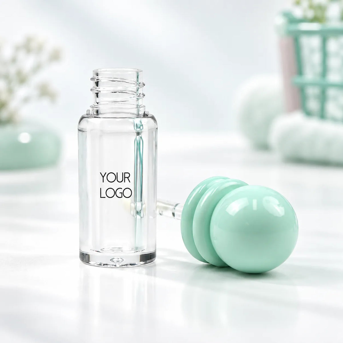 Open round lip gloss container with a clear bottle, mint-green double-ring ball cap and visible logo area