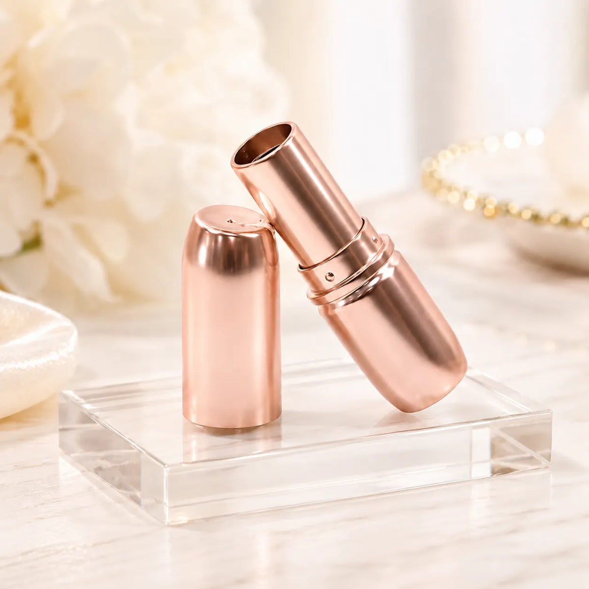 Rose gold lipstick packaging with metallic lipstick tube, empty inner cup, matching cap, and transparent display stand for luxury cosmetic brands